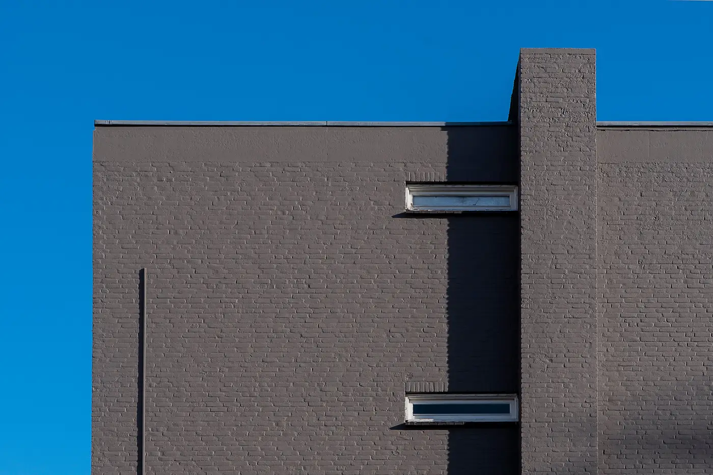 A commercial building's flat roofline and parapet wall against a clear blue sky.