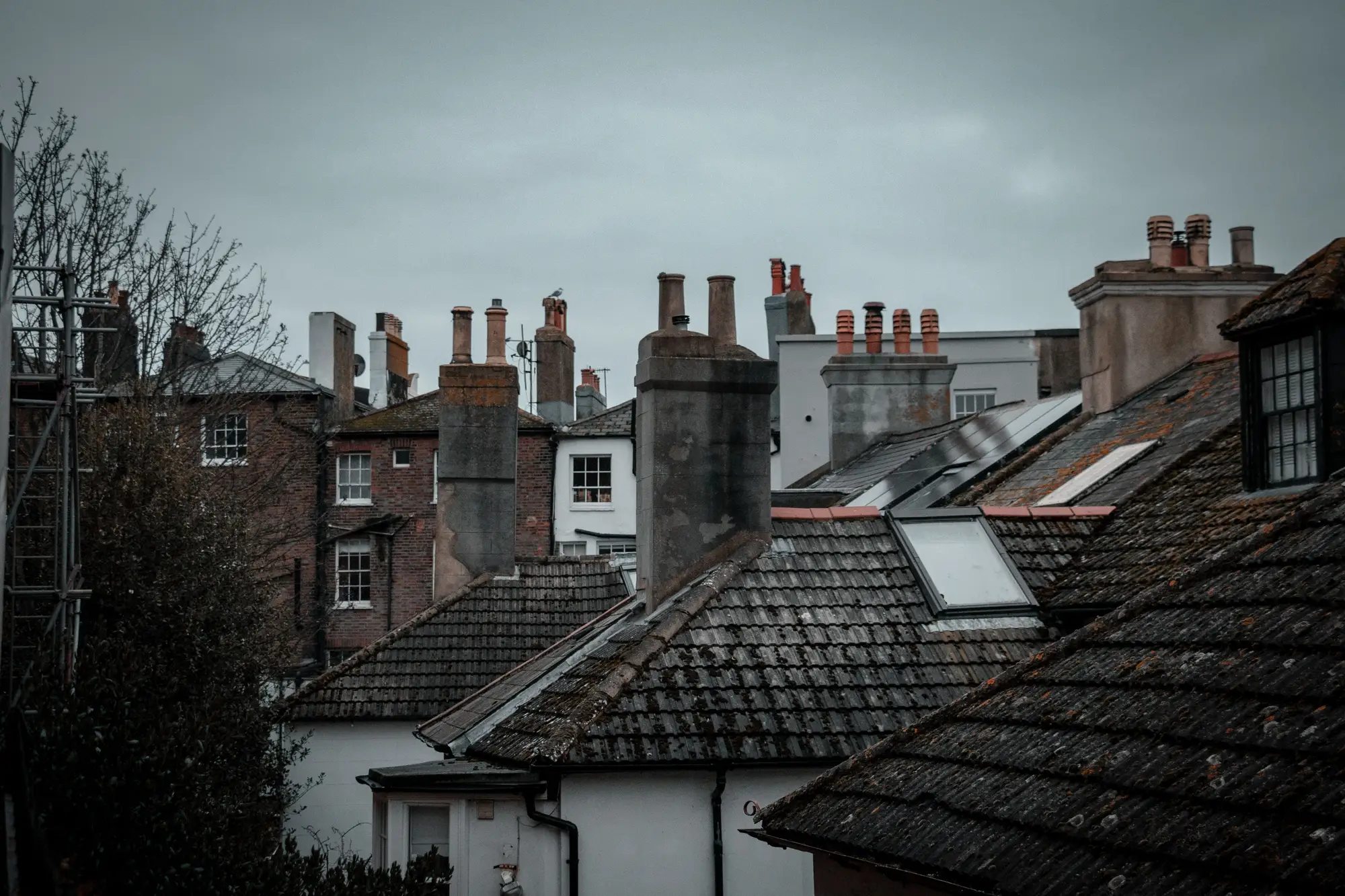 Slate and tile roofs with brick chimney stacks on a grey day in an English seaside town